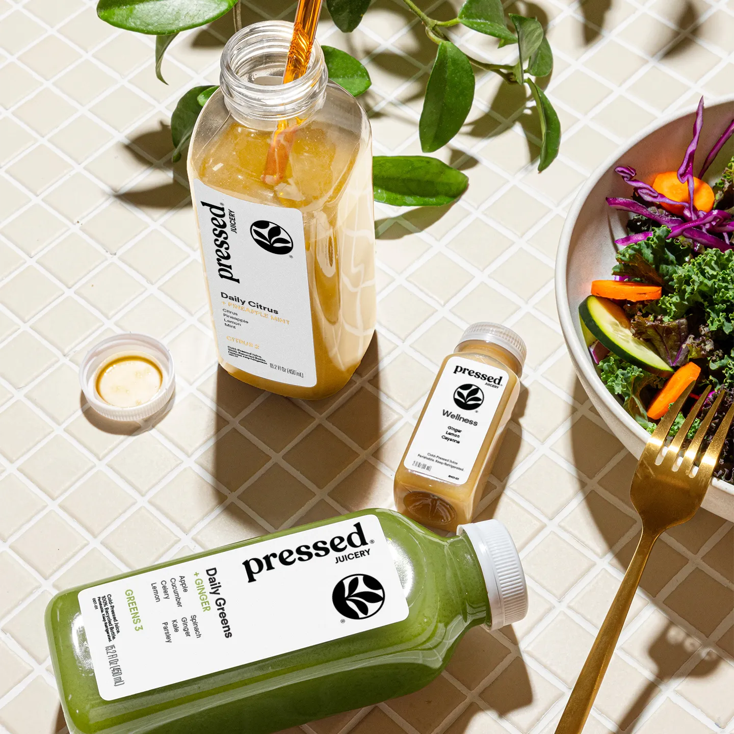 Bottles of 'pressed' juice on a table with a salad and fork