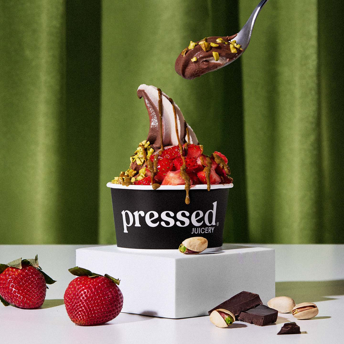 Pressed Juicery Dubai-Style Chocolate Sundae with strawberries and chocolate on a green background.