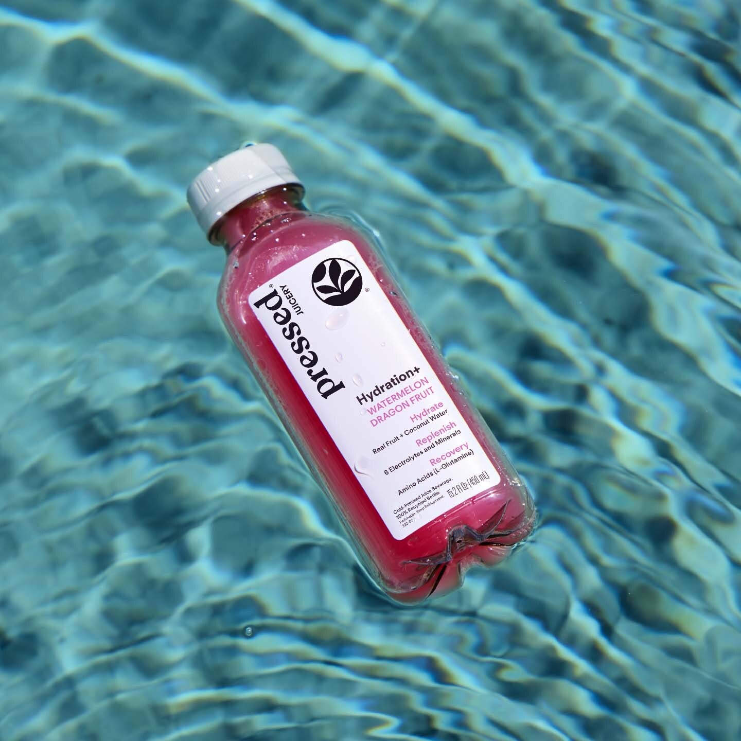 Pressed Juicery Hydration+ Watermelon Dragon Fruit bottle floating on blue pool water.