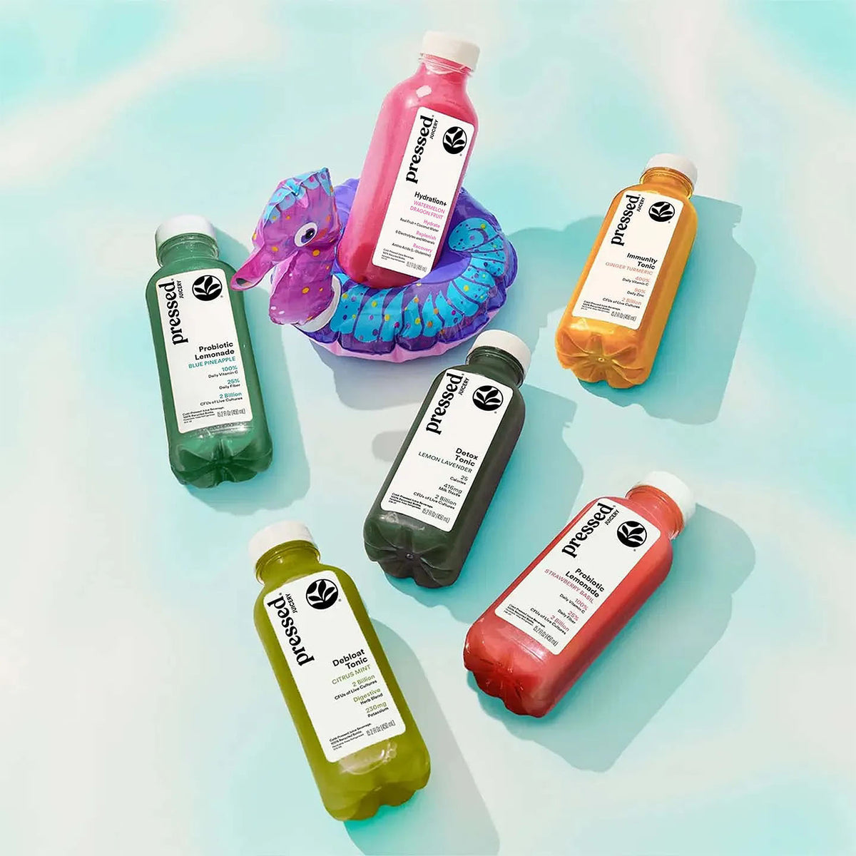 Assorted bottles of pressed juice on a gradient background