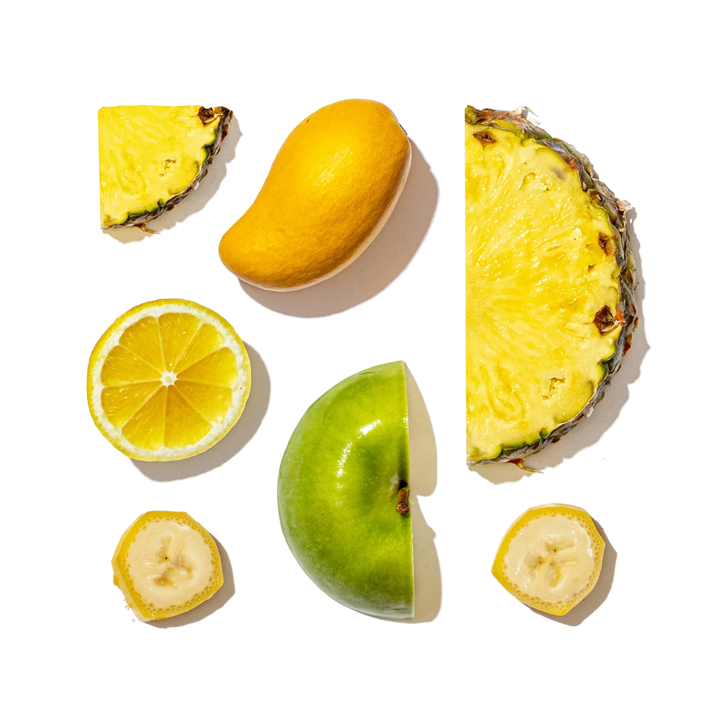 Collection of sliced fruits including pineapple, lemon, lime, and banana on a white background