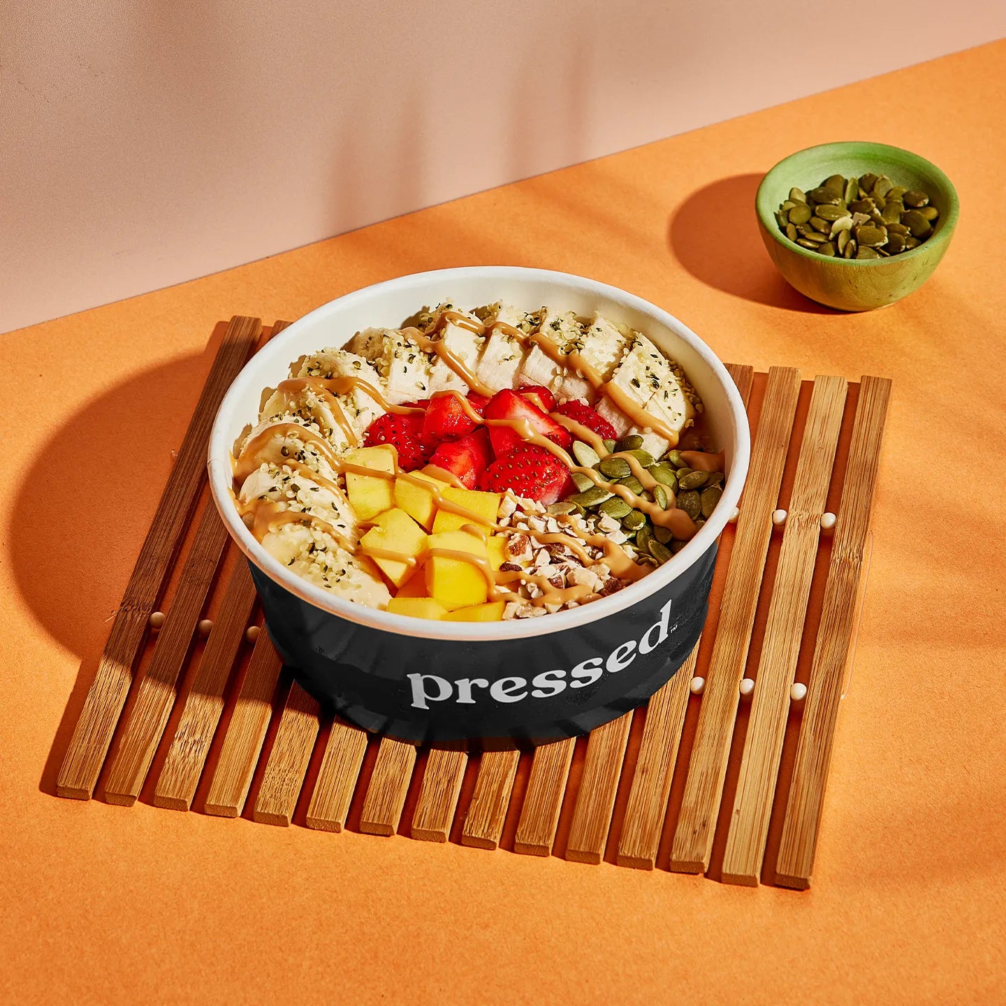 Bowl of salad with fruit on a wooden board and orange background