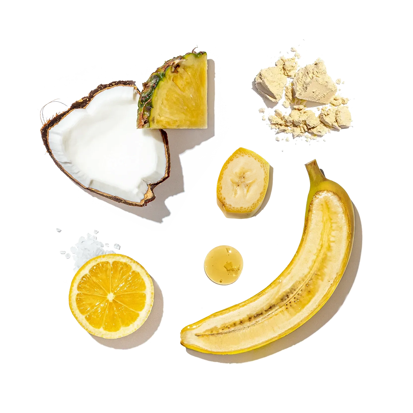 Ingredients for Pressed Juicery Tropical Protein Freeze, including banana, apple, lemon, pineapple, and coconut, on a white background.