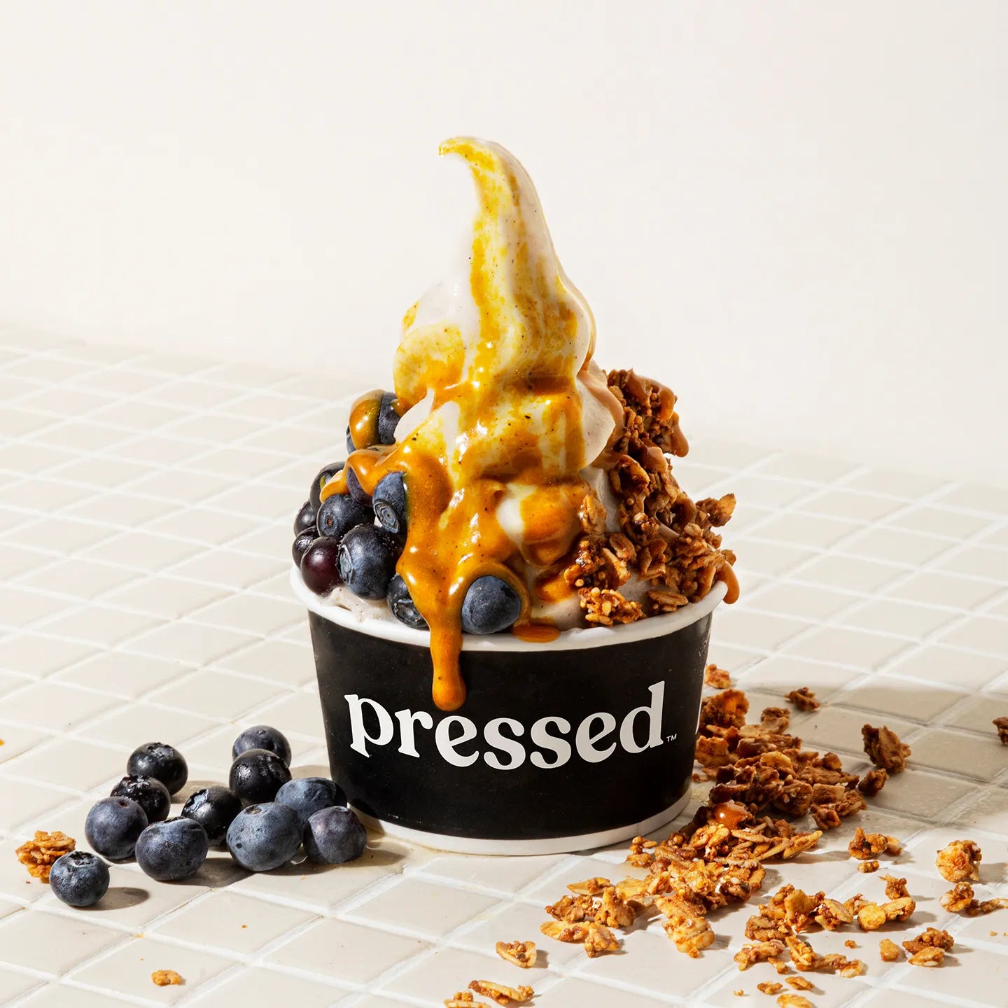 Pressed Juicery Vanilla Freeze with blueberries and granola on a light background.