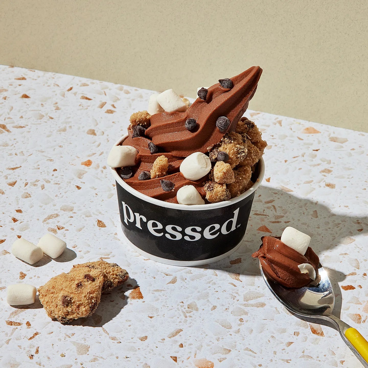 Pressed Juicery Chocolate Freeze with toppings on a textured surface.