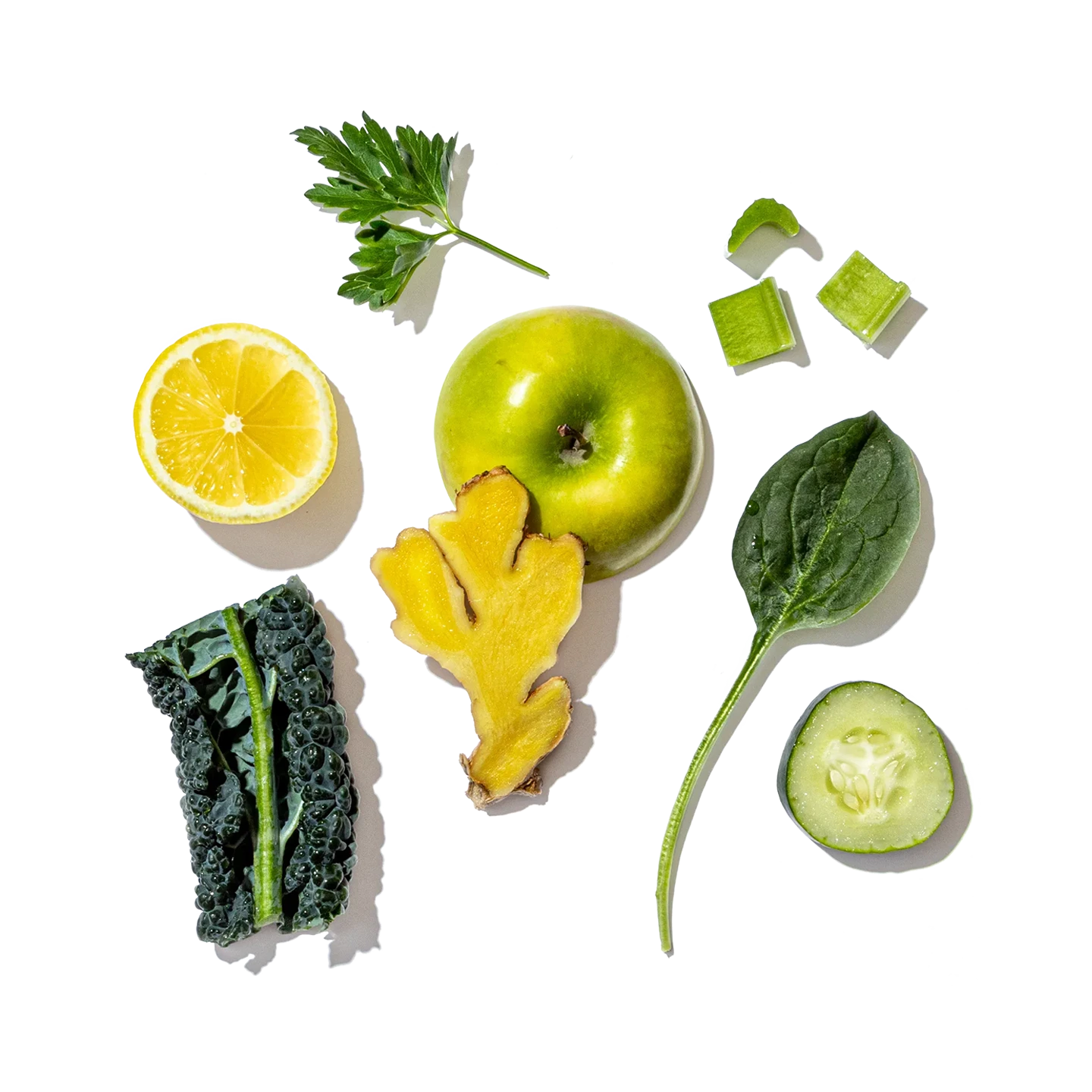 Assorted green fruits, vegetables, and a lemon on a white background