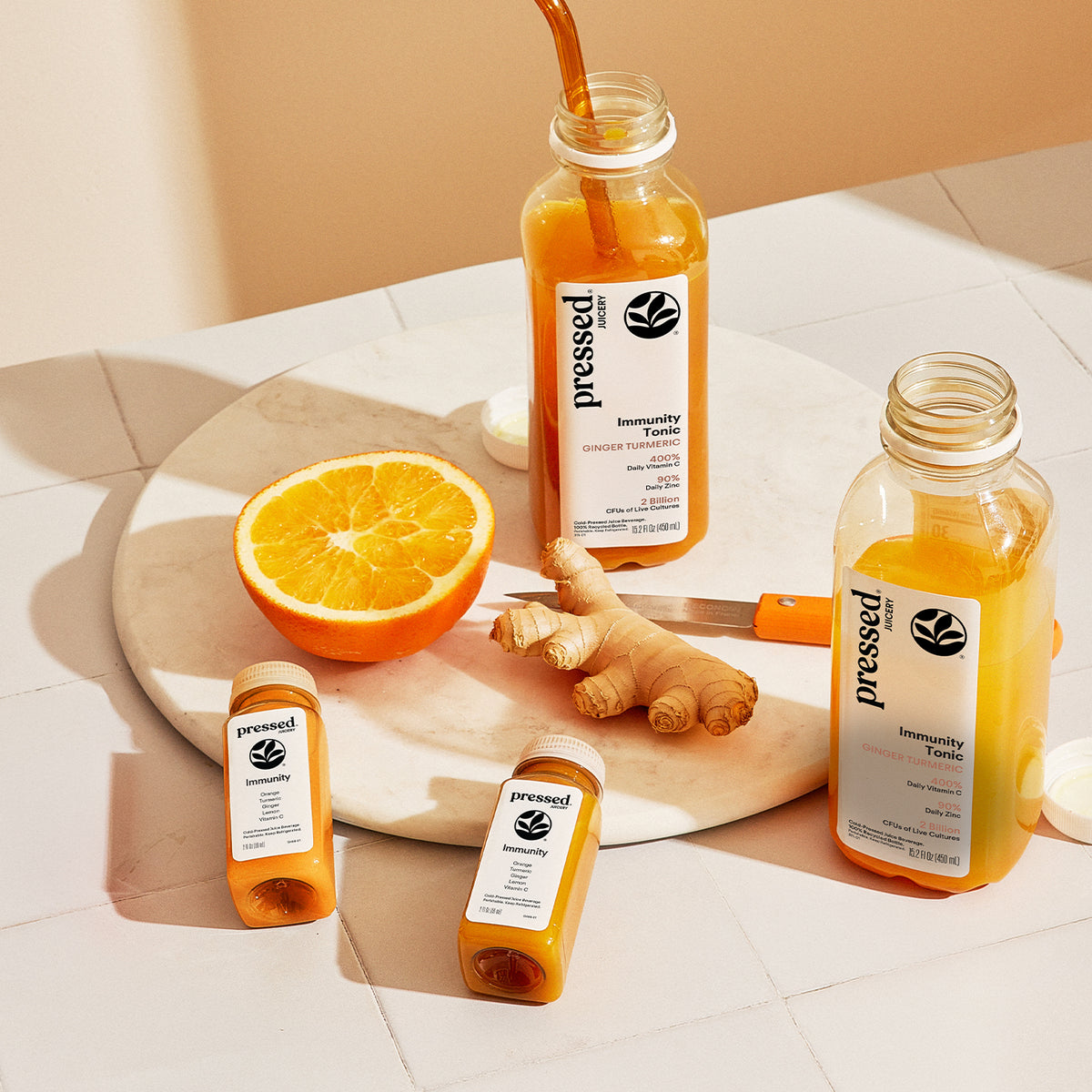 Pressed Ginger + Turmeric Immunity Pack with Immunity Shots and Immunity Tonics styled with fresh ginger and orange.