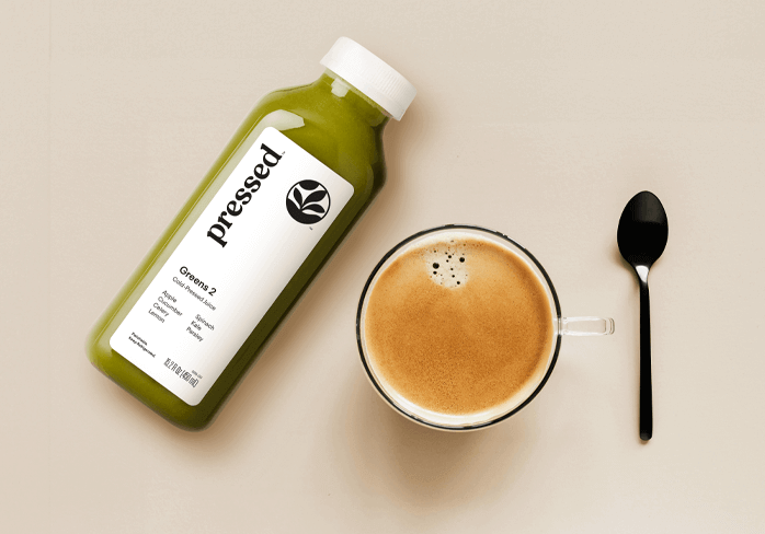 A bottle of Pressed green juice next to a cup of coffee and a spoon