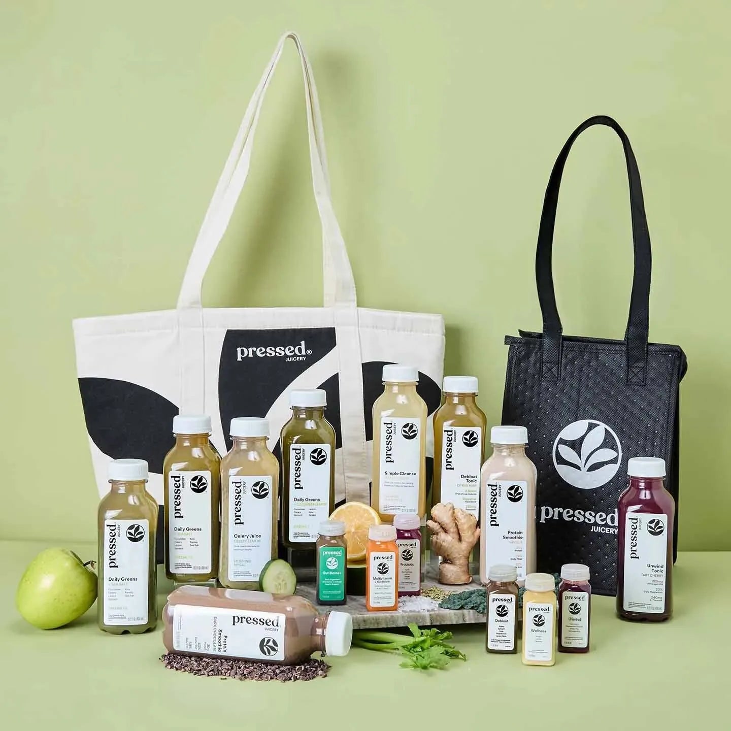 Collection of 'pressed' brand products including bottles, jars, and a tote bag on a green background.