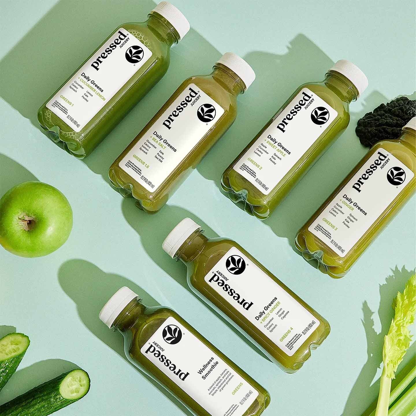 Bottles of 'pressed!' juice with green vegetables on a light green background