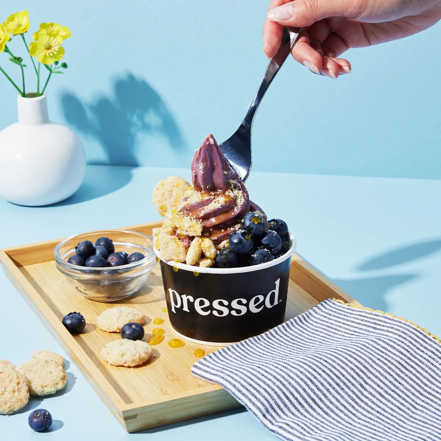 Dessert with blueberries and cookies on a wooden tray, featuring a 'Pressed' container.
