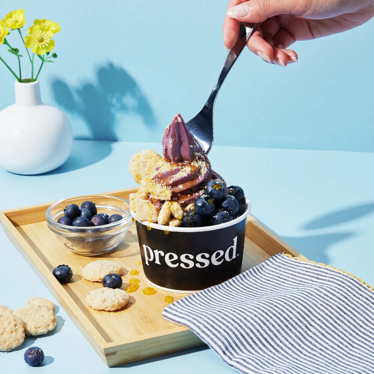 Dessert with blueberries and cookies on a wooden tray, featuring a 'Pressed' container.
