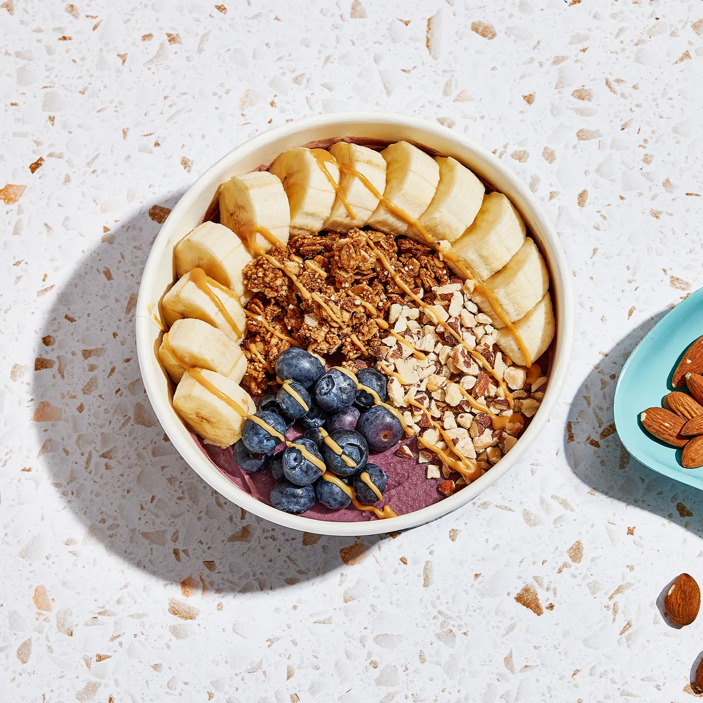 Fruit and granola bowl on a light speckled surface