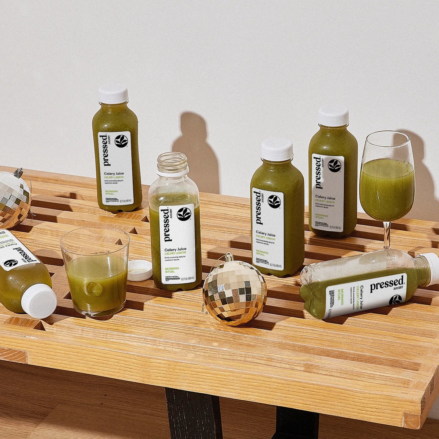 Bottles and glasses of green juice on a wooden surface with 'pressed' branding.