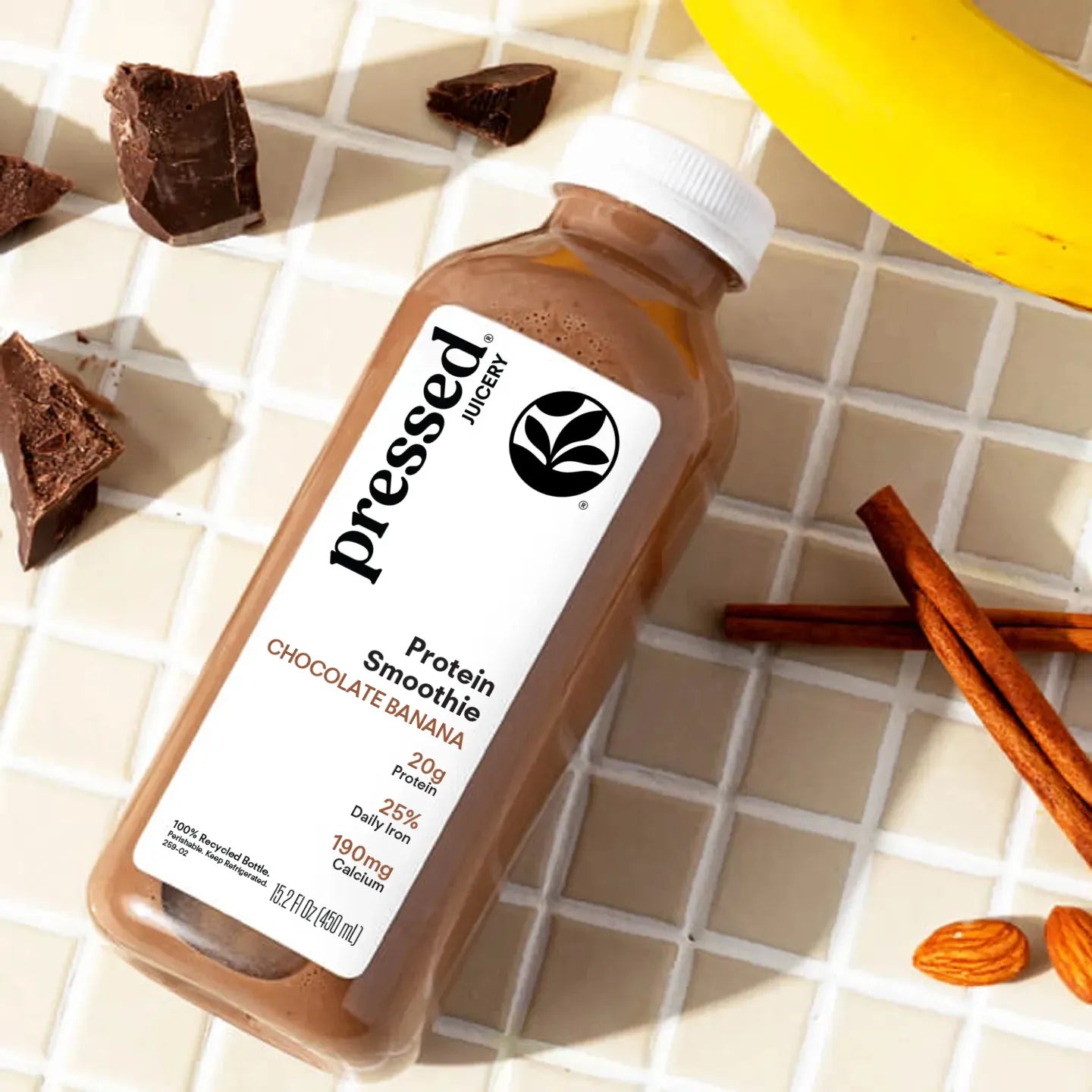 Bottle of Pressed Juicery Protein Smoothie with ingredients on a tiled surface