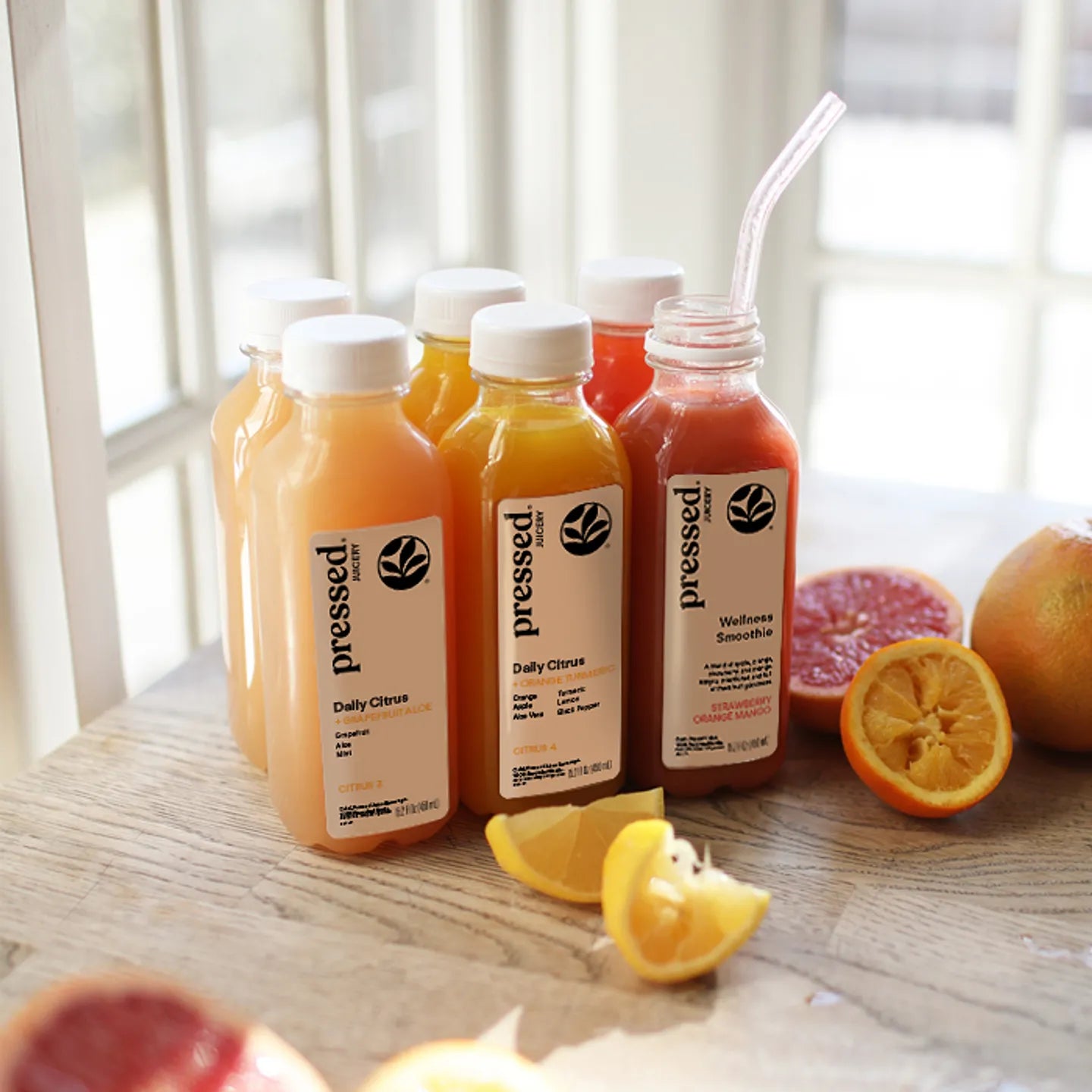 Bottles of 'pressed' juice on a table with fruits
