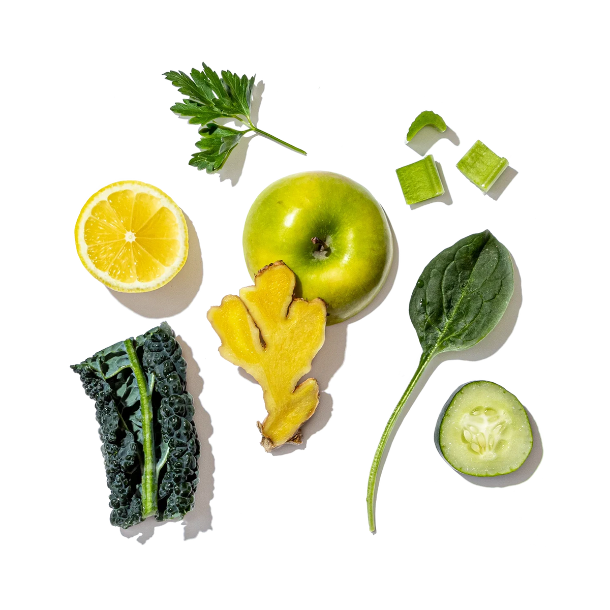 Assorted green fruits, vegetables, and a lemon on a white background
