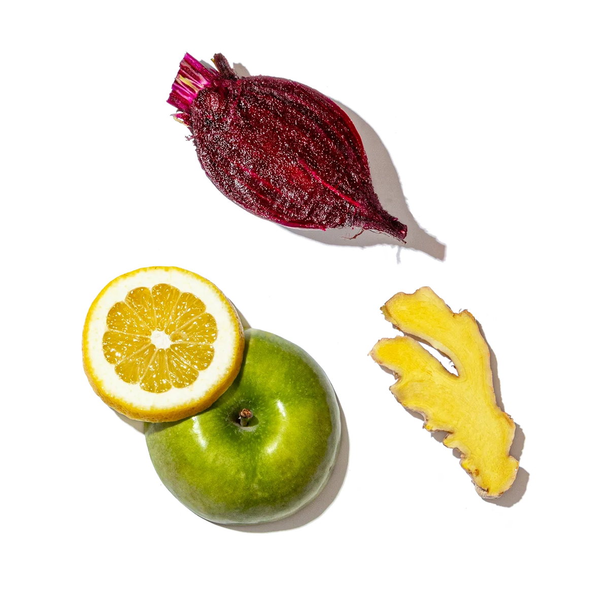 Fruits and vegetables including a beet, lemon, apple, and ginger on a black background