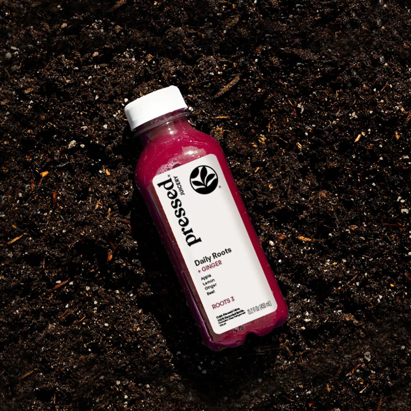 Bottle of 'presses' Daily Roots juice on a dark, textured surface