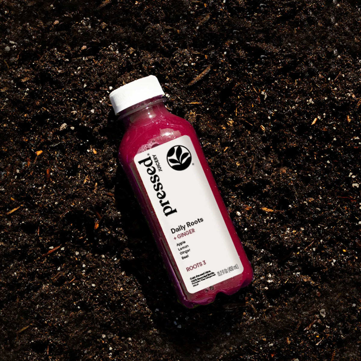 Pressed Juicery Daily Roots 3: Ginger Juice on a dark textured surface.