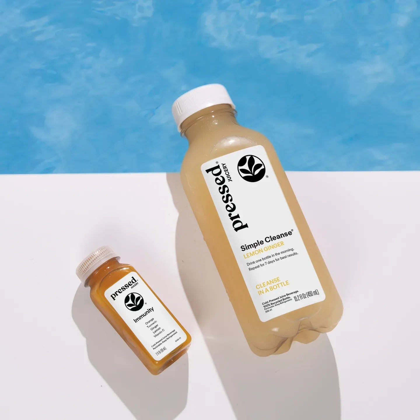 Two bottles of pressed juice against a blue and white background