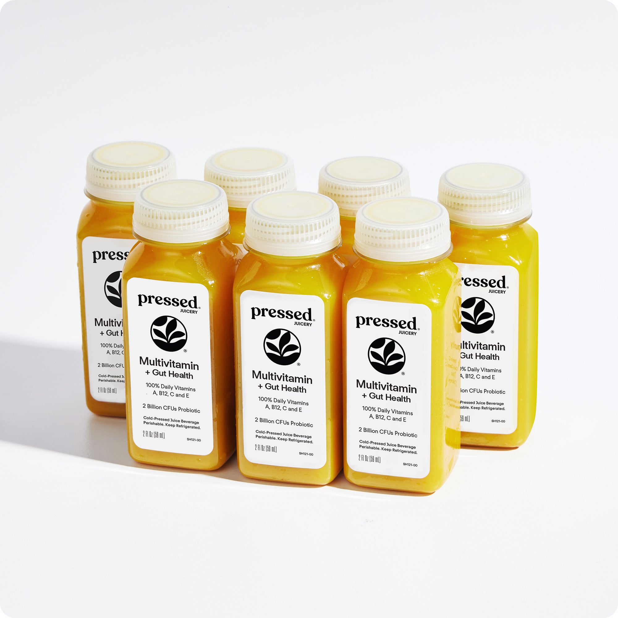 Six small plastic bottles of Pressed Multivitamin + Gut Health juice arranged in two rows on a clean white background. The bottles contain a bright yellow-orange liquid and have white labels with black text and logo.
