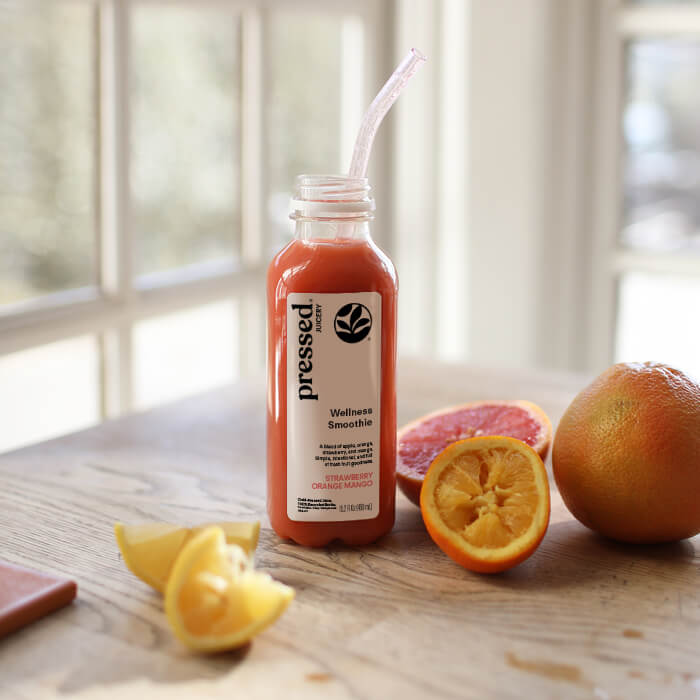 Bottle of 'pressed' wellness smoothie with fruits on a wooden surface
