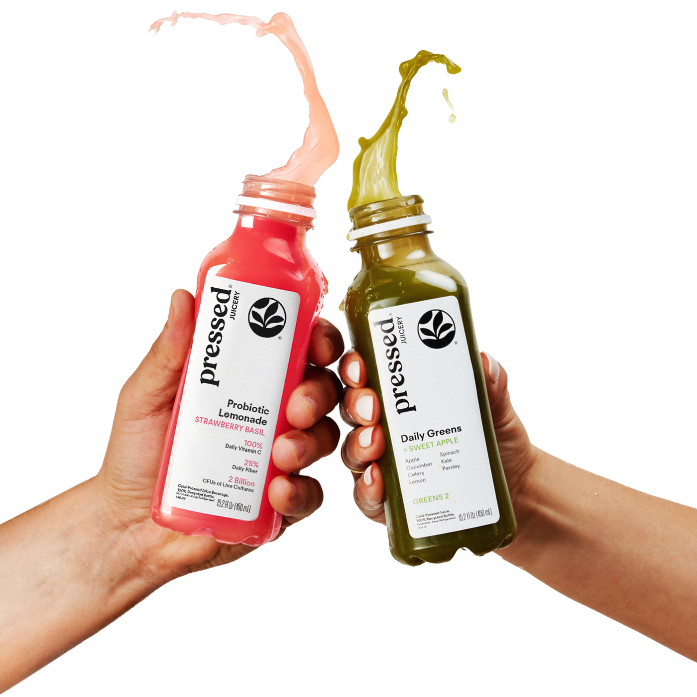 Two hands holding pressed brand bottled juices, one pink strawberry lemonade and one green daily greens, with liquid splashing from the open tops against a white background.