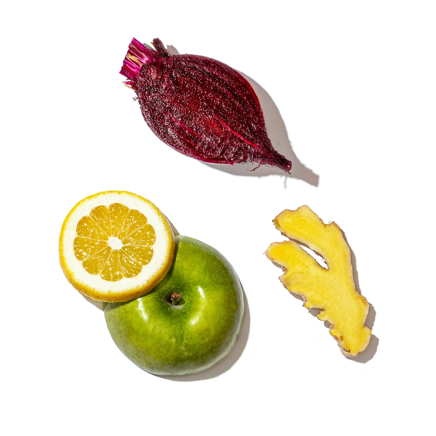 Fruits and vegetables including a beet, lemon, apple, and ginger on a black background