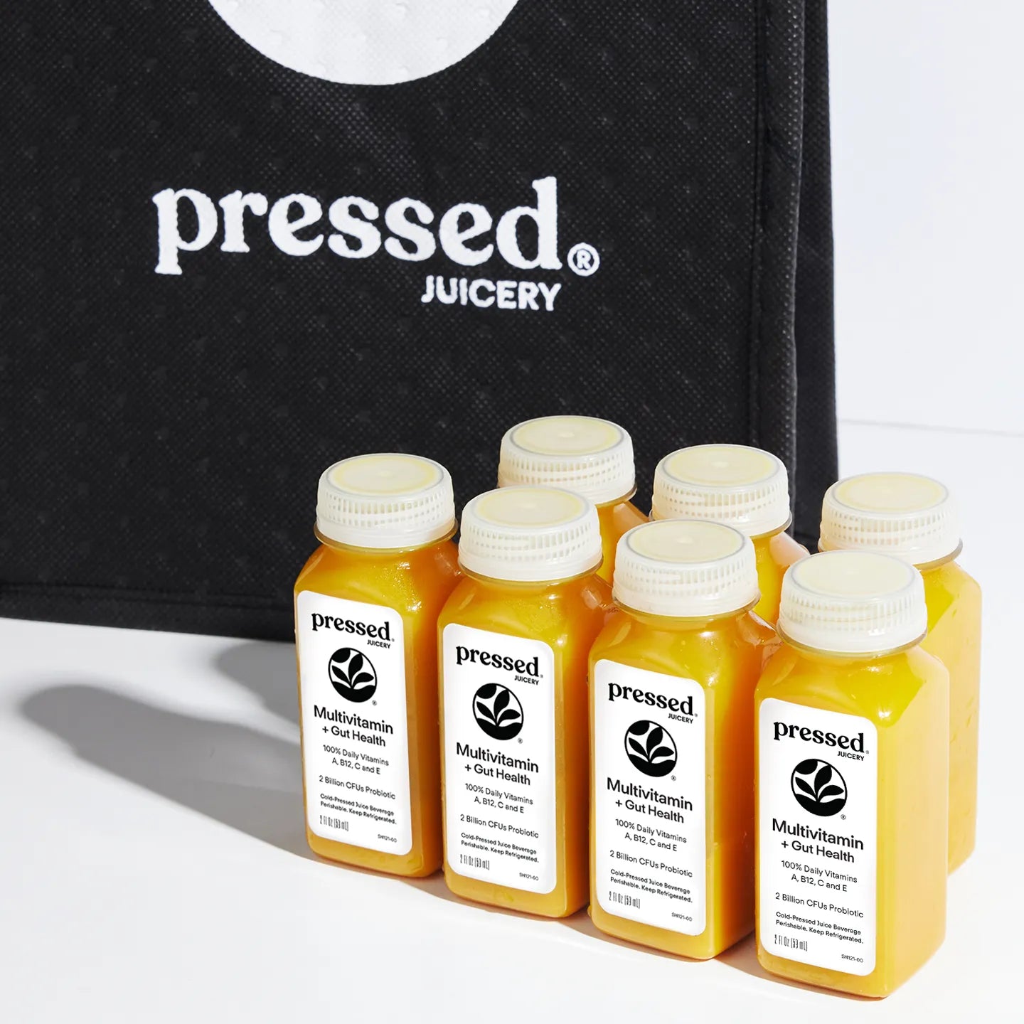 Bottles of 'pressed' juicery with a black bag in the background