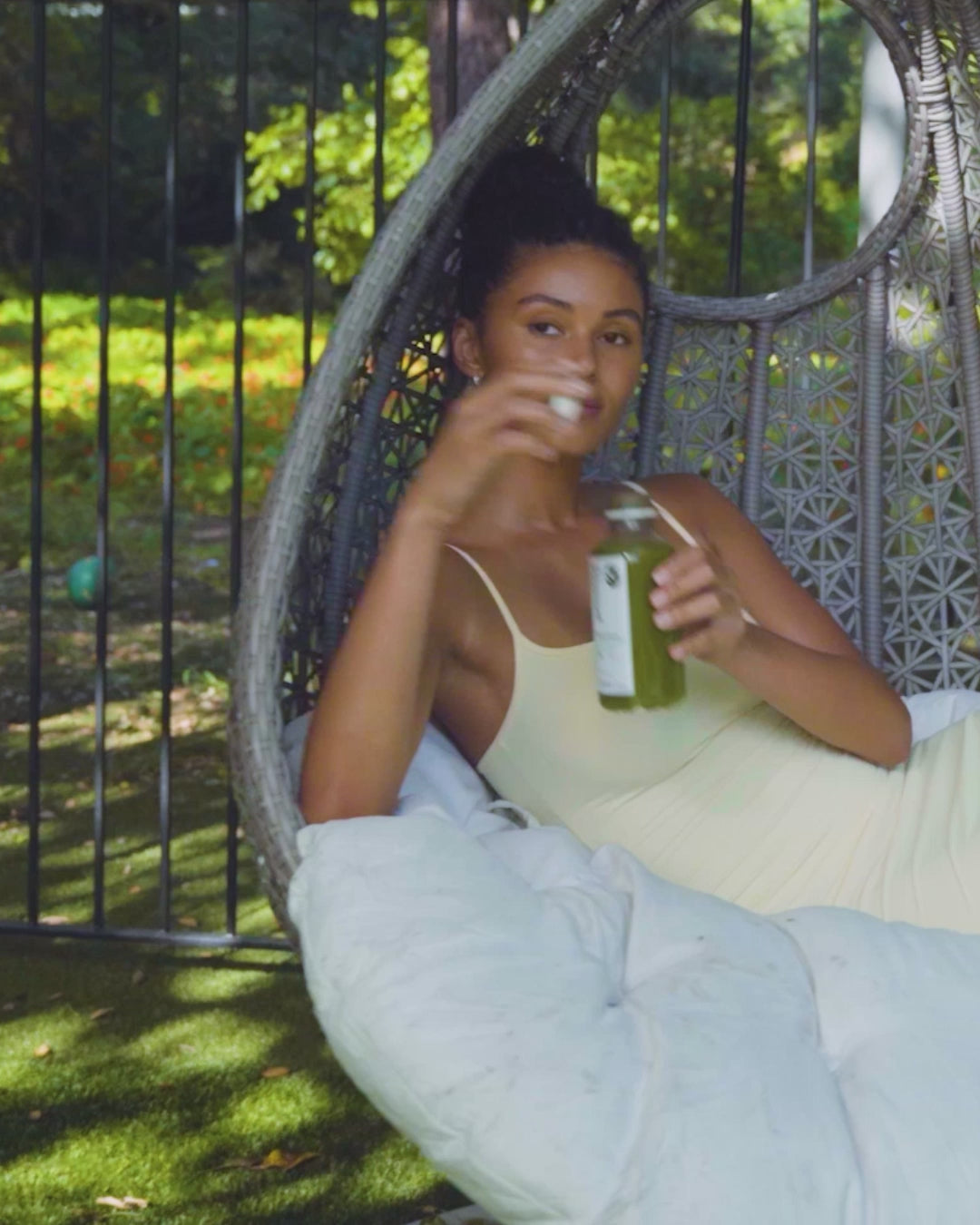 Person drinking a Pressed Juicery cold-pressed green juice while relaxing outdoors.