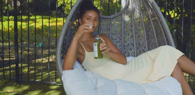 Person drinking a Pressed Juicery cold-pressed green juice while relaxing outdoors.