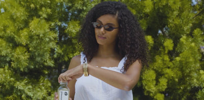 Woman enjoying Pressed Juicery Vacation Prep Pack by the pool with Simple Cleanse juice and Debloat Shot for debloat support.
