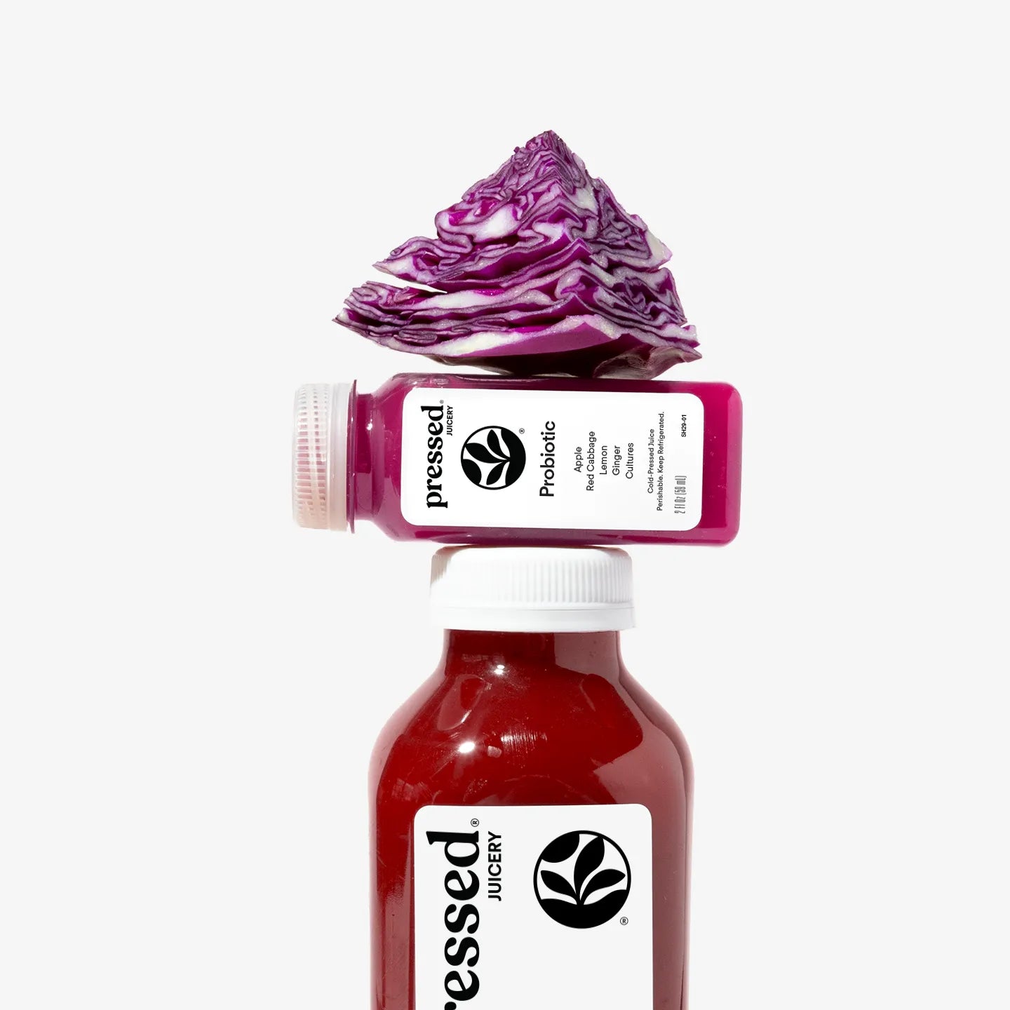Two bottles of Pressed Juicery with a dollop of purple juice on top against a white background